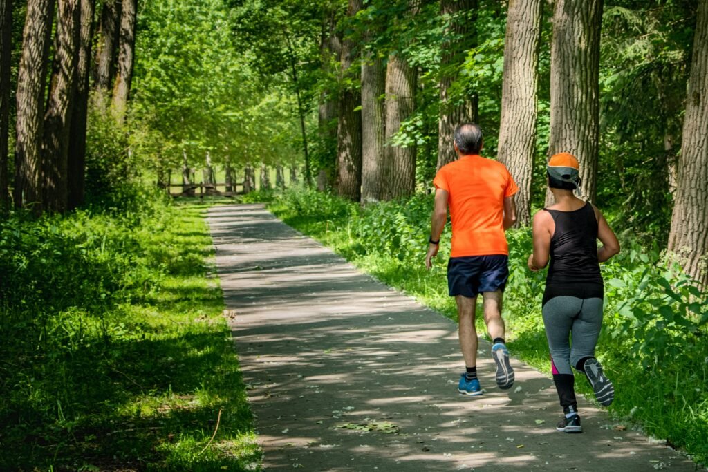 Two people go for a jog amidst greenery.